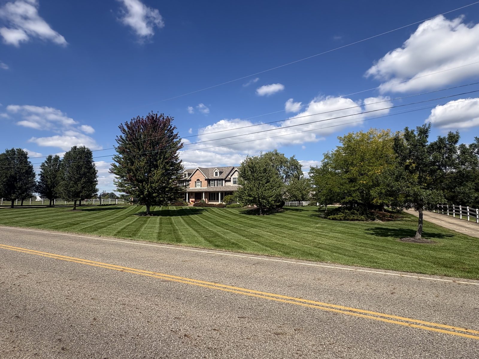 Striped front lawn in front of brick two-story home